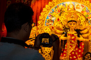 Young man photographing vibrant Durga idol during Kolkata Durga Puja festival