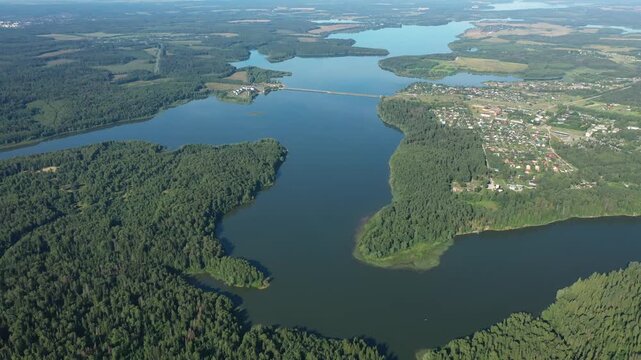 Drone moving backward over forest and river