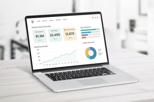Open laptop on light wooden desk showing startup performance dashboard with growth charts, client metrics, and top products in modern workspace