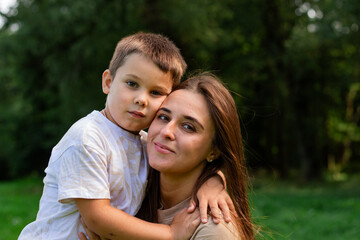 Obraz premium Mother kissing her cute preschool son on cheek. Candid portrait of parent and child. Mother's Day Concept