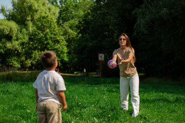 Fototapeta premium Active lifestyle of mom and son. Energetic scene of mother and boy running and kicking ball on sunny day. Ideal for themes of health, fitness, sports, and active living for all ages.
