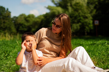 Fototapeta premium Mother with kid having fun in public green park. Happy mom laughing together with son. Quality leisure time outside.