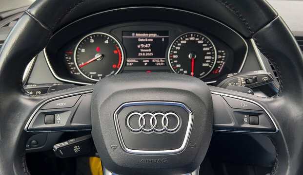 The high-quality interior of an Audi Q5 shows the dashboard with classic round gauges and a digital display.