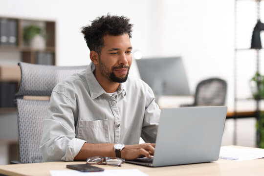 Man working on laptop at table in office - Powered by Adobe