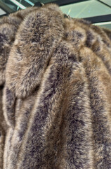 Fluffy faux fur winter jackets on a clothes rack in a department store 