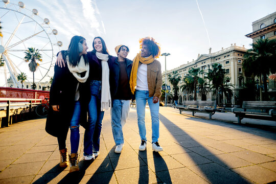 Diverse group of young friends having fun together outdoors on winter. Millennial student people laughing walking in city street enjoying day off. Youth community and friendship concept. - Powered by Adobe