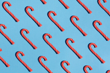 Seamless food pattern made of Christmas red striped candy canes on blue background. Minimal abstract concept. Christmas and new year background