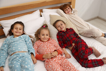 Cute children in pajamas on bed at home