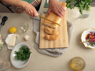 Anonymous person slices white bread on kitchen table. Food, recipes. Lifestyle and hobbies.