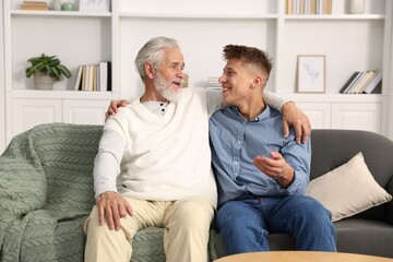 Father and son hugging on sofa at home