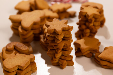 Gingerbread cookies are stacked in various shapes, ready for a Christmas celebration. The preparation reflects a traditional cooking activity filled with holiday cheer and creativity.