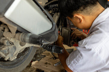 motorcycle mechanic works on the engine and cooling system in a repair shop, focusing on maintenance and technical adjustments.