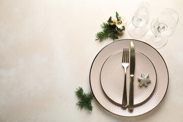 Festive table setting with Christmas decor on beige background, flat lay. Space for text