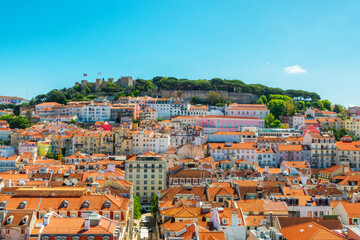 Obraz premium Panoramic view of Lisbon city with red rooftops and Sao Jorge Castle on the hill, Lisboa, Portugal. Old town skyline of Portuguese architecture in Alfama district. Travel and tourism in Europe
