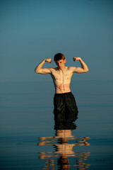 Obraz premium Teenage Boy Flexing In The Sea