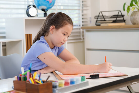 Caucasian preteen girl writing colorful notebook with pencil during elementary classroom art education concentrating creativity childhood learning practice discipline study inspiration