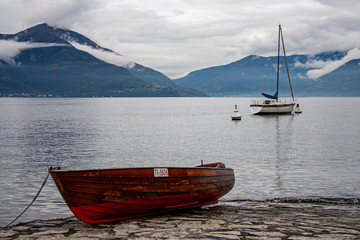Holzboot im Hafen und Segelboot vor dem Hafen von Ascona am Lago Maggiore in der Schweiz