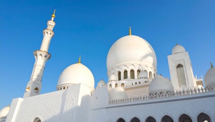 Obraz premium Beautiful white mosque with domes and tall minaret under blue sky, elegant Islamic architecture and cultural heritage exterior view.