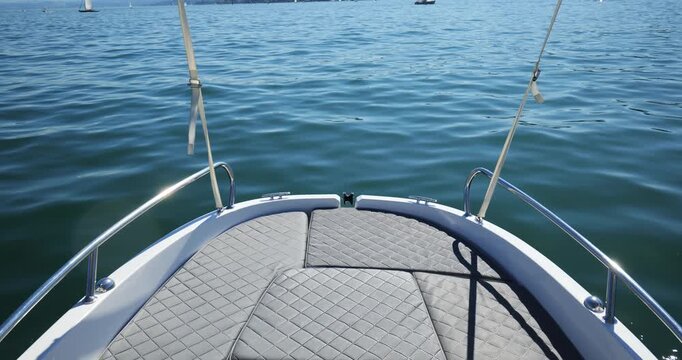 Small electric rental boat sundeck bow on lake water. Wide angle footage, sunny late summer day, marine vinyl deck cushions, no people