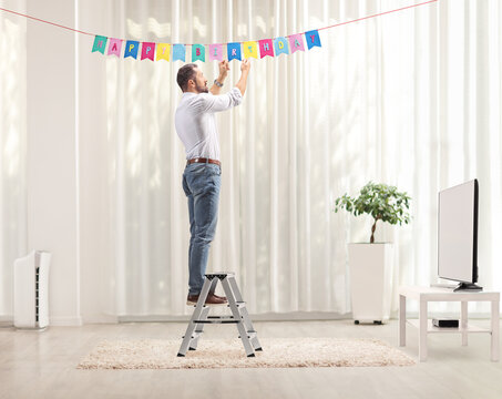 Man on a ladder putting birthday decorations