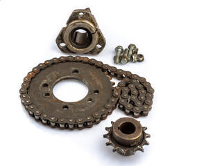 A close-up of a dirty, oily, and greasy chain, sprockets, and wheel hub on an old motorcycle against a white background. The image captures the essence of repair and maintenance.