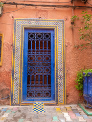 A Vibrant Blue Door with Intricate Wrought Iron and Colorful Mosaic Tiles on a Terracotta Wall in Marrakech, Morocco