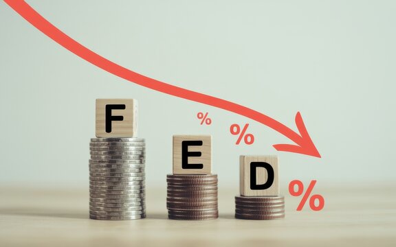 Falling interest rates depicted by coins and wooden blocks spelling FED with a downward arrow