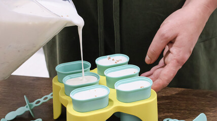 A girl pours ice cream mixture into IKEA molds. Making ice cream at home