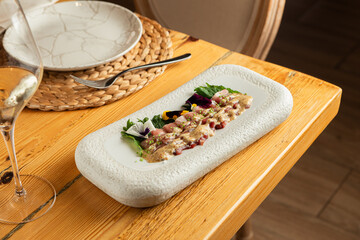 Raw tuna dish with sauce in luxury wooden interior restaurant