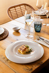 Grilled cod fillet with sauce in luxury wooden interior restaurant