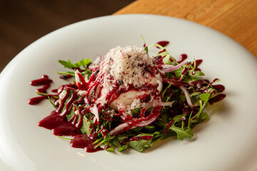 Designer dish with cheese, salad and raspberry sauce in luxury wooden interior restaurant