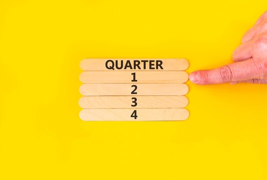 1st first quarter 1 symbol. Concept word Quarter 1 on beautiful wooden sticks. Beautiful yellow background. Businessman's hand. Business, happy 1st first quarter 1 Q1 concept. Copy space.