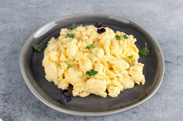 Scrambled eggs with green onions on a gray plate on a gray background. Healthy breakfast. 