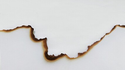 A sheet of white paper with scorched and burned edges. Scorched paper texture with burned torn...