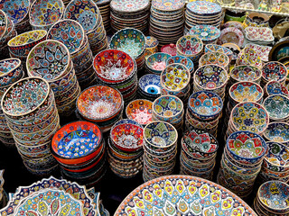 Colorful handmade ceramic bowls with traditional oriental patterns displayed at a market. Souvenir and decor concept. Top view.
