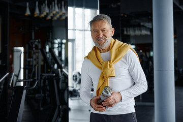 Portrait of a senior man in the gym holding a water bottle