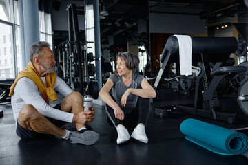 Mature couple are having a conversation while resting in a gym