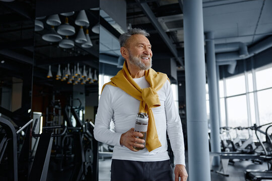 Active senior man at gym with water bottle, wearing sport clothing