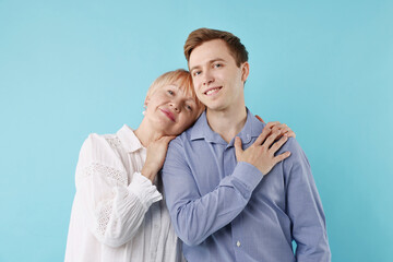 Mother hugging her son on light blue background