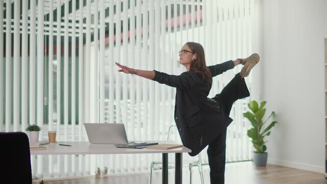 Positive Workplace and Healthy Culture. Office Manager Performs Balancing Spine and Leg Stretch Beside Desk to Build Strength Improve Flexibility Enhance Focus and Support Energized Office Environment