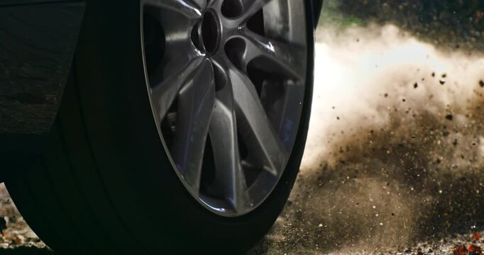 Slow Motion lose-up of a car wheel spinning and kicking up dust on a dirt road. Dynamic slow-motion footage capturing power and movement a1000 fps.