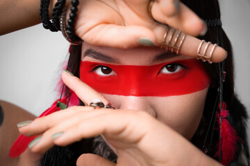 Shaman woman with face painting on light grey background, closeup