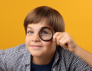 Little boy with magnifying glass on yellow background