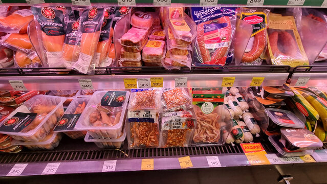 A refrigerated supermarket display case with a selection of meats and snacks.  