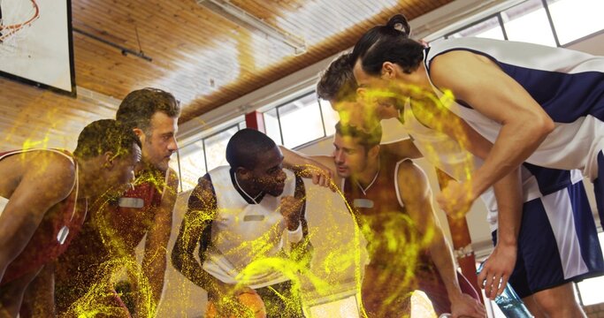 Huddling six basketball teammates strategizing in gym, with hoop and glowing yellow particles