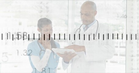 Two professionals wearing coat and scrubs studying chart in hospital corridor, with stethoscopes