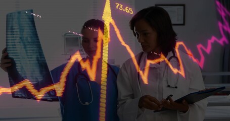 Analyzing X-ray, nurse in scrubs, doctor in coat taking notes in exam room, financial graph overlay