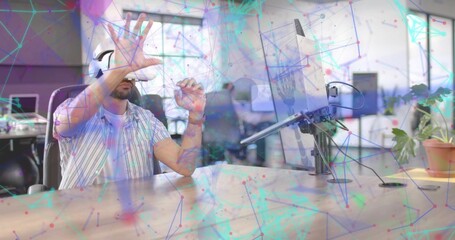 Obraz premium Gesturing using VR headset, man wearing striped shirt at open office desk with monitor, copy space