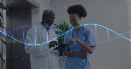 Doctor in labcoat and nurse in scrubs viewing tablet in clinic hallway, with DNA helix, stethoscope