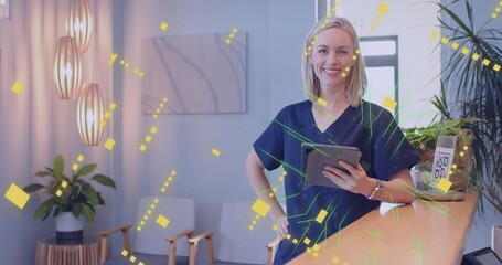 Standing female medical professional holding tablet behind wooden desk in clinic lobby, copy space